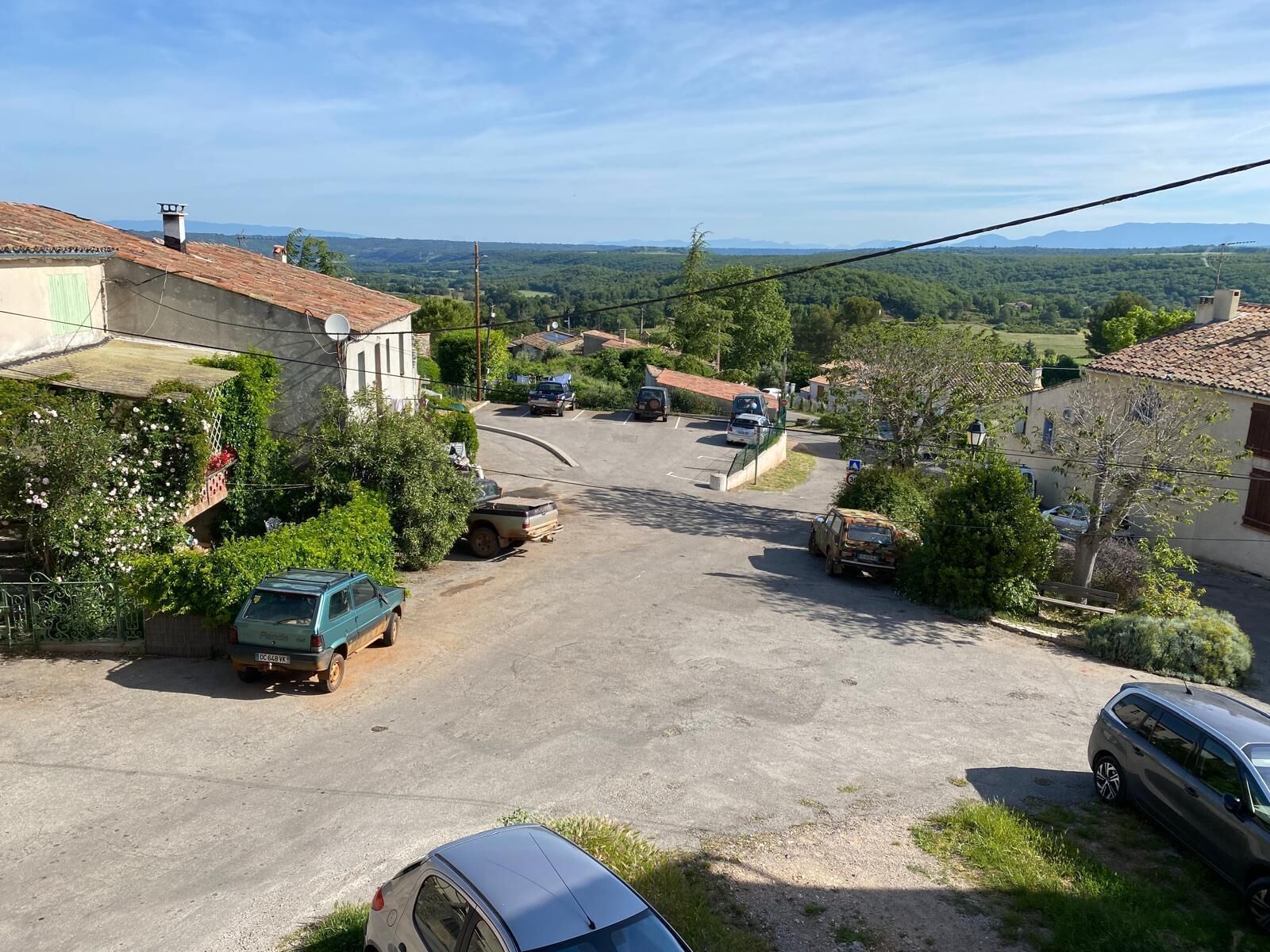 Una calle residencial con casas, automóviles estacionados y una vista despejada del campo.