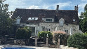 Een stenen huis met twee verdiepingen, een zwembad, stenen trappen en een tuin.