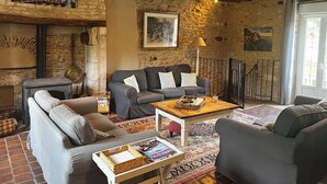 Een gezellige woonkamer met een open haard, stenen muren en een rustiek houten plafond.