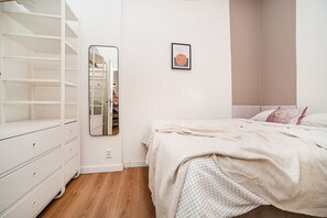 A bedroom with a bed, a wardrobe, a mirror, and a framed picture on the wall. - Charming, modern, 1-bed flat by Museum of Prague (Praha 8)