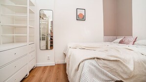 Un dormitorio con una cama, un armario, un espejo y un cuadro en la pared.