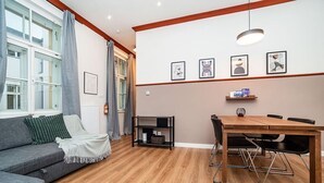 Una sala moderna con un sofá gris, mesa de comedor de madera y sillas negras.