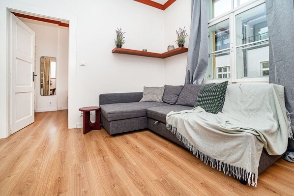 A modern living room with a sectional sofa, a small side table, and a window with curtains.