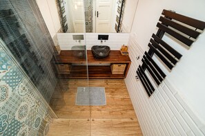 A bathroom with a wooden vanity, a glass shower enclosure, and a patterned floor. - Charming, modern, 1-bed flat by Museum of Prague (Praha 8)