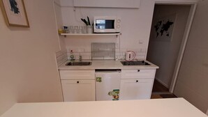 Una cucina compatta con forno a microonde, lavello e piccolo frigorifero.