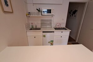 A compact kitchen with a microwave, sink, and a small refrigerator.