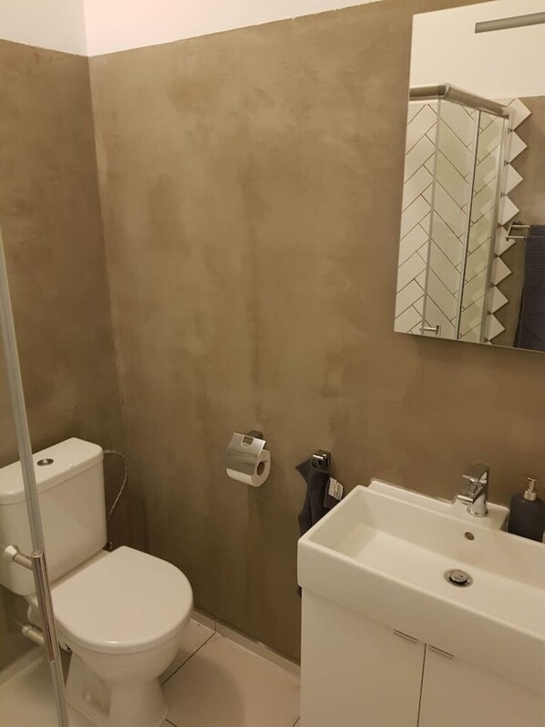 A bathroom with a toilet, a sink, and a mirror. - Stylish one bed apartment by Namesti Miru (Hlavní město Praha)