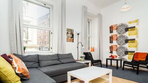A modern living room with a grey sofa, a white coffee table, and a patterned wall.