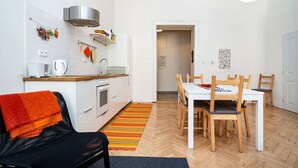 A modern kitchen with white cabinets, a stainless steel range hood, and a wooden dining table with chairs.