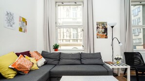 A modern living room with a grey sectional sofa, patterned cushions, a white coffee table, and a floor lamp.