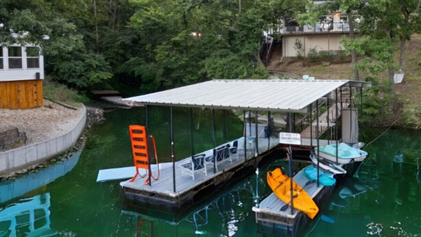 A dock with a covered seating area, a boat, and a small building. - Anchors Away-Private Dock & Slip + Fire Pit + Kayak + Grill (Sunrise Beach)