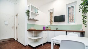 Eine kleine Küche mit weißen Schränken, einer Holz Arbeitsplatte und einem integrierten Fernseher.