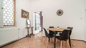 A dining area with a round table, black chairs, a clock on the wall, and a window with a hexagonal pattern. - Classic Old town stay (Praha 1)