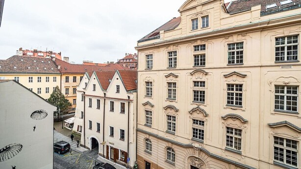 A street view of historic buildings with a mix of architectural styles, including a building with a curved facade and another with a traditional pitched roof. - Classic Old town stay (Praha 1)