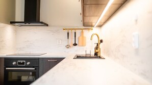 Et moderne køkken med indbygget ovn, stålvask og en ophængt grydeholder.