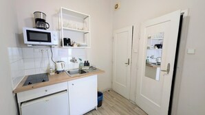 Una cocina compacta con microondas, cafetera y pileta. Hay una cubierta de madera y un mueble bajo de color blanco.