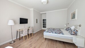 Un dormitorio moderno con cama, escritorio, sillas, televisor y lámpara.