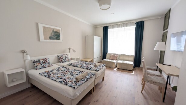 Habitación de hotel con dos camas, un escritorio, una silla y un televisor.