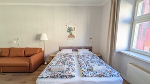 A bedroom with two beds, a sofa, and a small table.