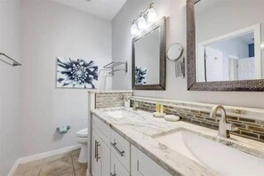 Une salle de bain avec un lavabo blanc, un miroir et des toilettes. On y trouve également des éléments décoratifs sur les murs et un porte-serviettes.