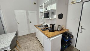A compact kitchen with a wooden countertop, white cabinets, a microwave, and a coffee maker. There is a small dining table with chairs.