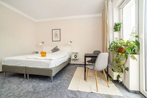 A bedroom with a bed, bedside table, chair, and a potted plant by the window. - Cozy studio with terrace by tram (Praha 3)
