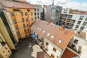 A multi-story building with a tiled roof, balconies, and a courtyard. - Cozy studio with terrace by tram (Praha 3)