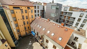 Um edifício de vários andares com telhado em telhas, varandas e um pátio.