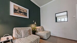 A room with two beige sofas, a small table with a tray, a framed picture on the wall, and a floor lamp.