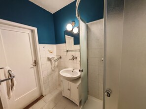 A bathroom with a white sink, a mirror, and a shower.