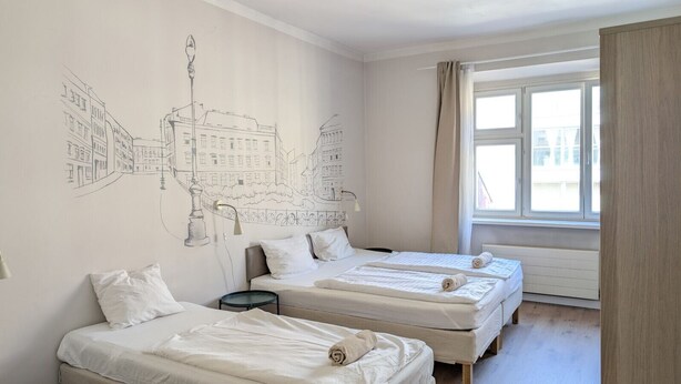 A bedroom with two beds, a wall mural, a window with curtains, and a radiator.