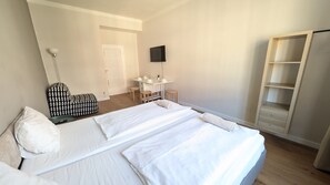 A hotel room with a large bed, a desk, a chair, a TV, and a wardrobe. - Comfortable apartment sleeps 6 (Praha 3)