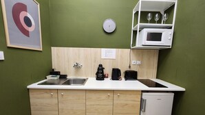 A compact kitchen with a sink, coffee maker, toaster, and a small refrigerator.