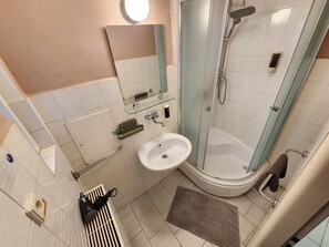 Ein Badezimmer mit Dusche, Waschbecken und Spiegel.