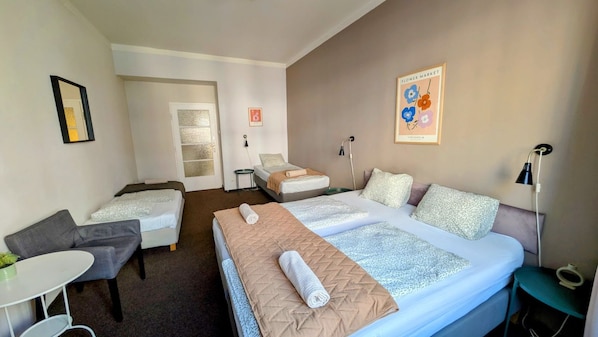 A hotel room with two beds, a sofa, a small table, and a chair.