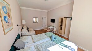 A bedroom with two beds, a desk, a chair, a mirror, and a wardrobe.
