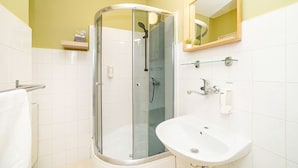 A modern bathroom with a glass-enclosed shower, a white sink, and a mirror above it. - Comfortable apartment sleeps 8 (Praha 3)