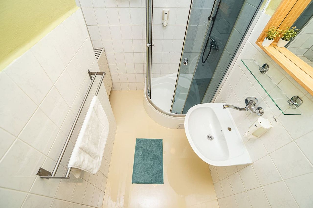 Een badkamer met een douchecabine van glas, een witte wastafel en een handdoekhouder.