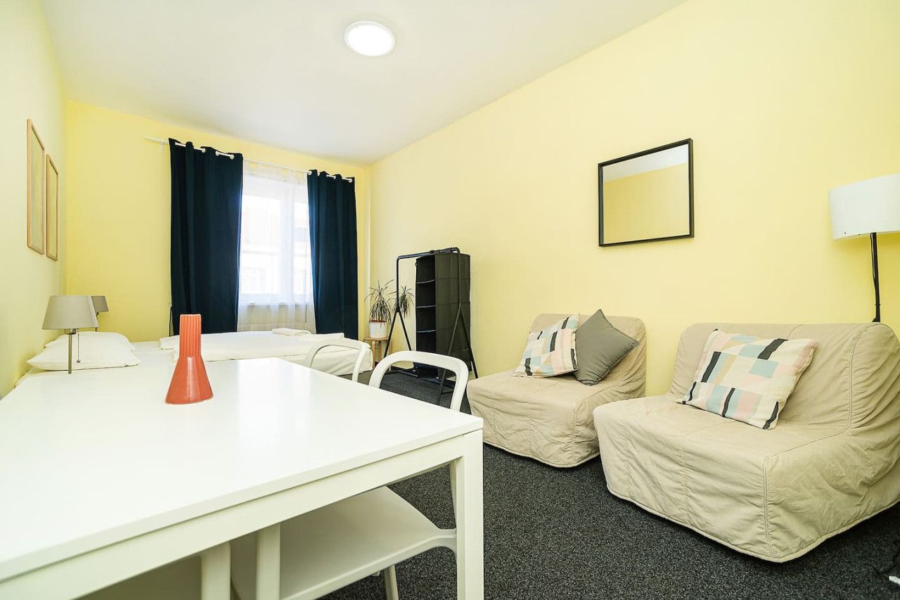 A room with a white table, two beige sofas, a black cabinet, and a mirror on the wall.