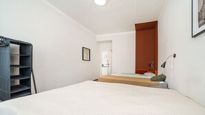A bedroom with a bed, a nightstand, a desk, and a chair. There is a door leading to a bathroom. - Comfortable apartment sleeps 8 (Praha 3)