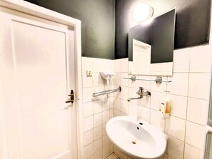 A bathroom with a white sink, a mirror, a towel rack, and a shower area. - Clean apartment easy location (Praha 3)