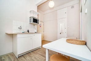 A compact kitchen with white cabinetry, a microwave, and a small countertop.