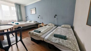 Une chambre avec deux lits simples, une petite table et une chaise.