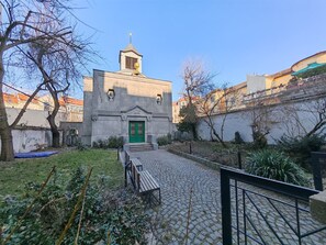 A courtyard with a stone building featuring a green door and a small tower.