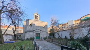 A courtyard with a stone building featuring a green door and a small tower.