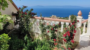 A balcony with a view of the sea, surrounded by greenery and red flowers. - Villa Tangier vispless pool with panoramic sea view  (Tangier)