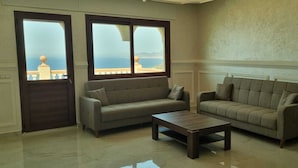 A living room with two sofas and a coffee table, large windows with a view of the sea, and a textured wall. - Villa Tangier vispless pool with panoramic sea view  (Tangier)