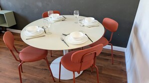 A round dining table with white plates, cutlery, and wine glasses set for four.