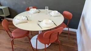 A round dining table with white plates, cutlery, and wine glasses set for four.
