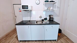 A compact kitchen with a microwave, sink, and coffee maker.